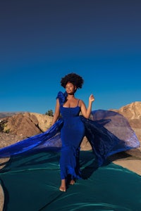 a woman in a blue dress standing in the desert