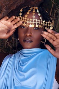 a woman in a blue dress with a gold crown on her head