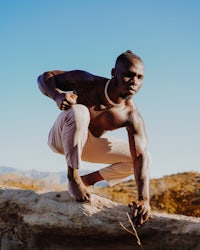 a man crouching on top of a rock