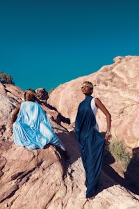 two people sitting on a rock in the desert