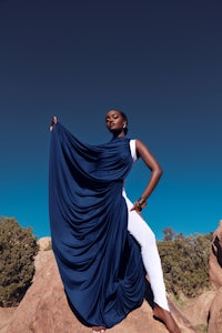 a woman in a blue dress posing on a rock